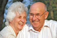 A husband and wife of 50 + years enjoy each other in the glow of a setting sun.